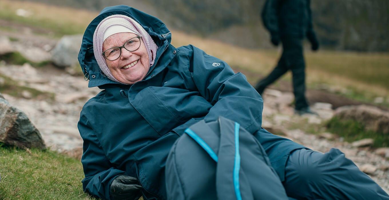 A member of Muslim Hikers resting on the hillside during a community hike — the quiet moment where a sponsorship promise gets made