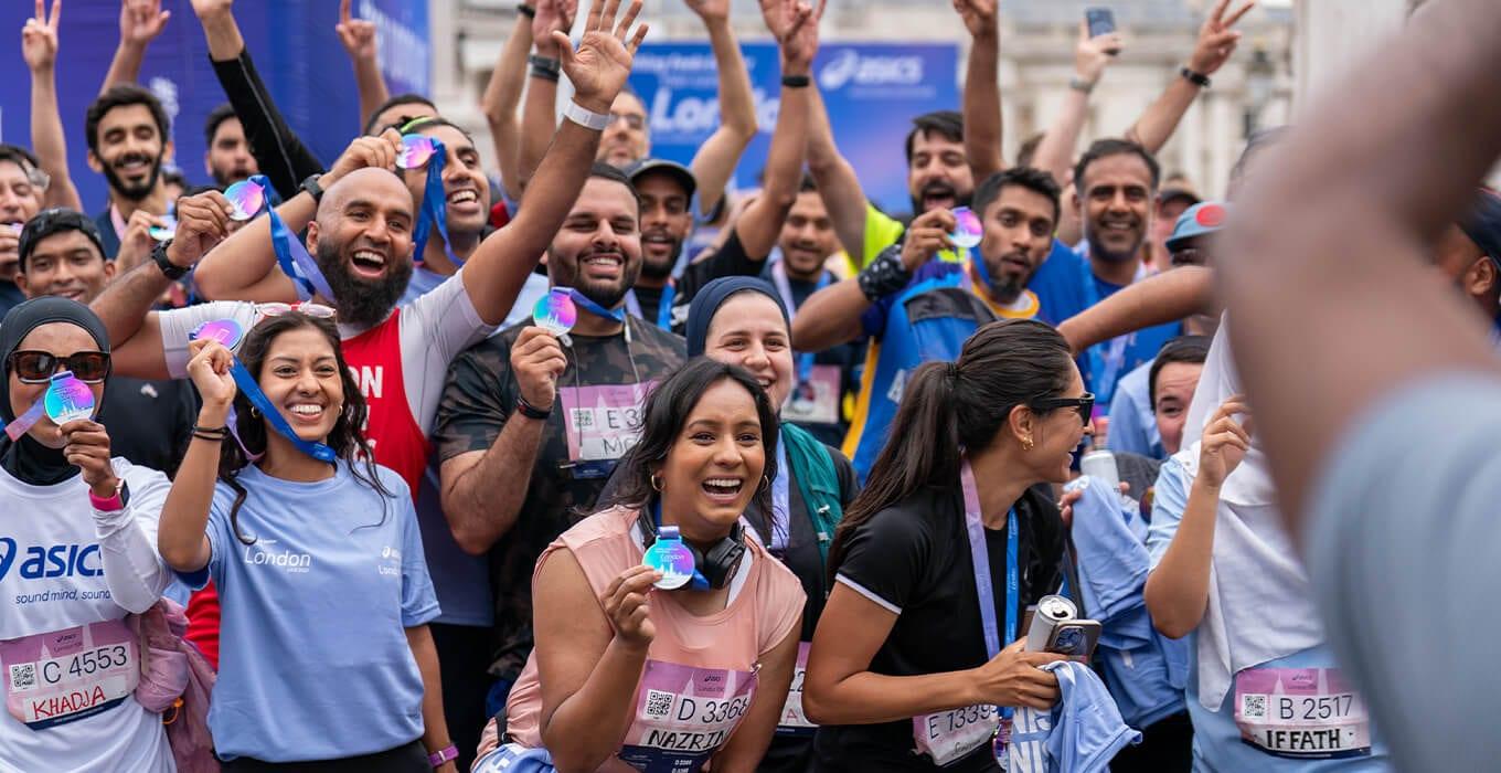 Muslim Runners community celebrating at the London Marathon finish line with medals raised — the moment where friends and family pledged sponsorship
